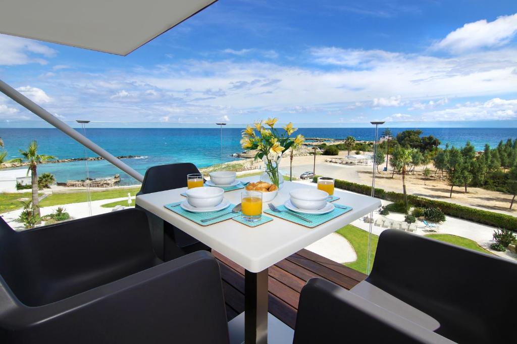 una mesa con un plato de comida en un balcón con vistas al océano en Apartment Josephine - Beachfront, en Protaras