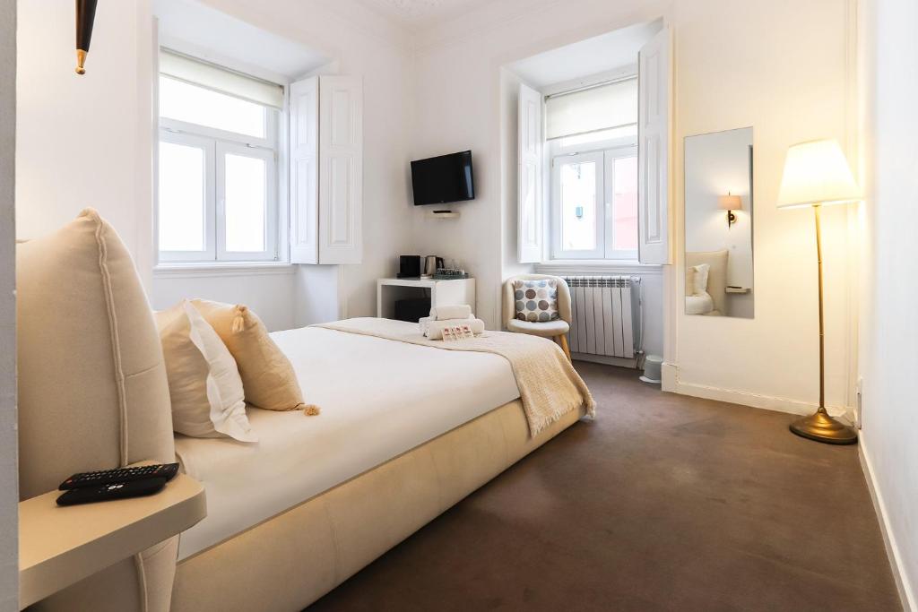 a white bedroom with a bed and two windows at Chiado Prime Suites by Homing in Lisbon