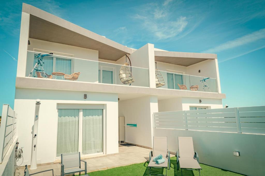 a white house with chairs and a balcony at Wayra Lodge [Kanchay] in Raposeira