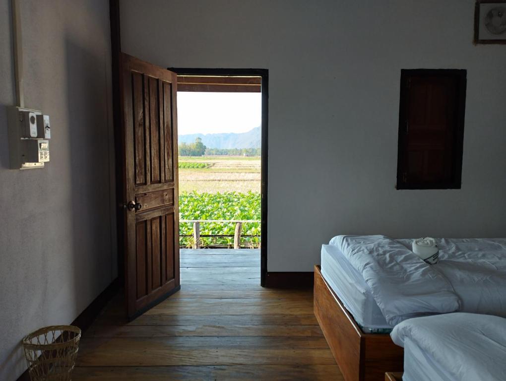 een slaapkamer met een bed en een deur naar een veld bij Konglor Khamchalern Guesthouse and Restaurant in Ban O