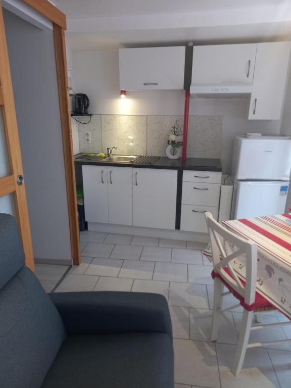 uma pequena cozinha com armários brancos e uma mesa em SNTL em Jonzac