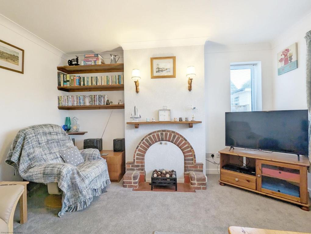 sala de estar con chimenea y TV de pantalla plana en Cissa en Chichester