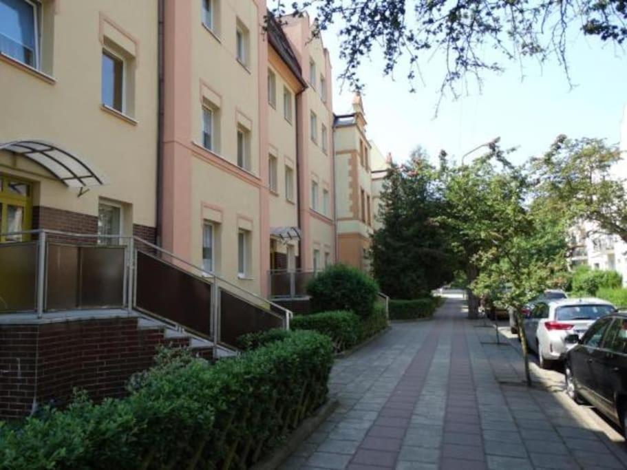 un trottoir devant un bâtiment avec des voitures garées dans l'établissement Apartament Blisko Morza Świnoujście, à Świnoujście