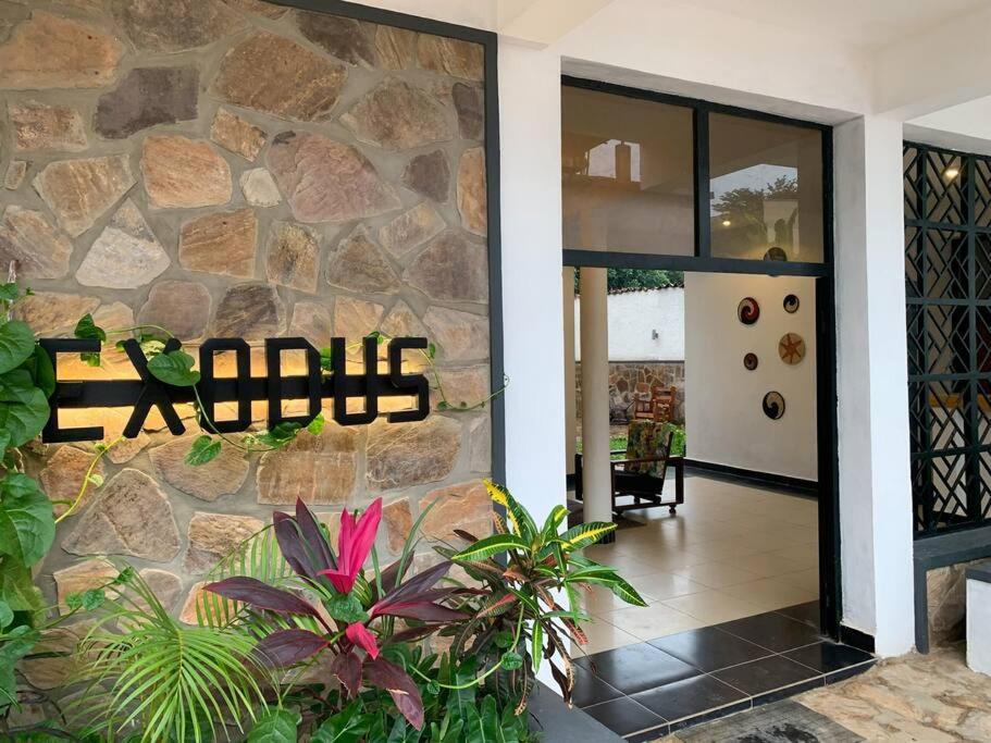 a lobby with a stone wall with a sign on it at Exodus Apartments in Bujumbura