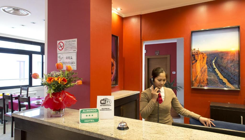 een vrouw staat aan een balie in een kamer bij Oasi Village Hotel in Milaan