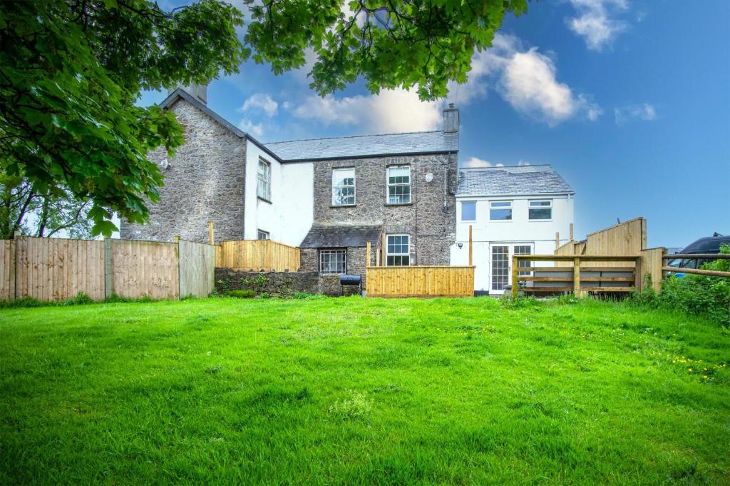 a house with a fence and a green yard at West Jordanston Farm Cottage - 4 Bedroom Cottage - St Florence in Tenby