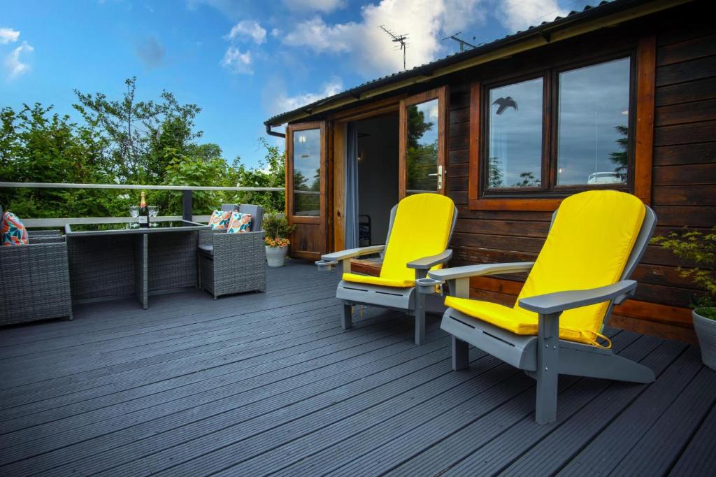 two yellow chairs on the deck of a cabin at The Lodge At Sheepswalk Farm - 2 Bedroom Lodge - Stepaside in Stepaside