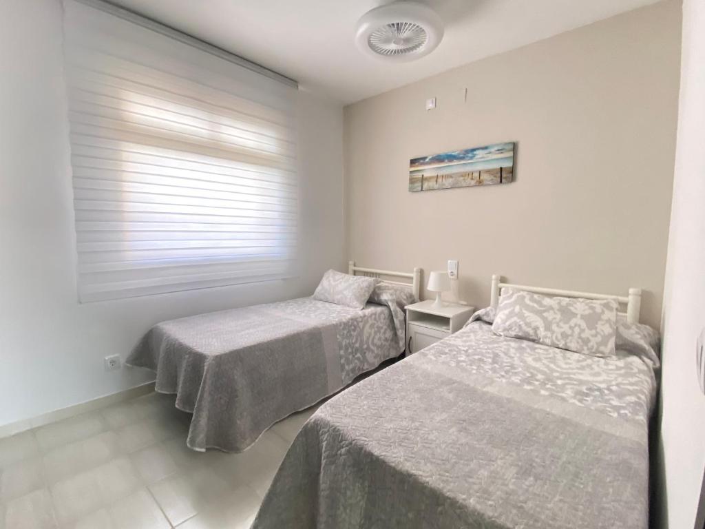 1 dormitorio con 2 camas y ventana en Versailles-mar, en Cambrils