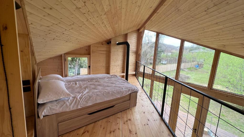 a bed in a wooden room with a balcony at Dumbo Eco Camp in Ozurgetʼi