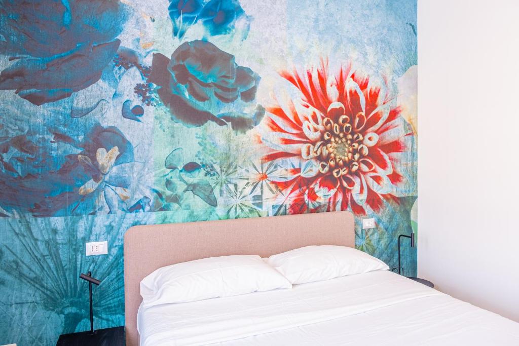 Cama en habitación con un mural de flores en Lilium Maris Hotel, en Bibione