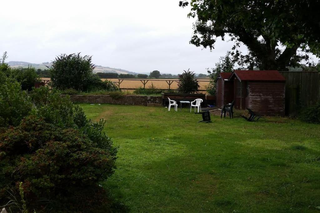a yard with two white chairs in the grass at A quiet self-contained flat close to Exeter. in Stoke Canon