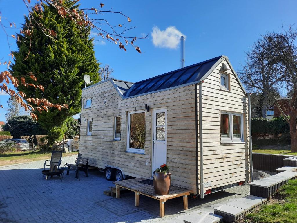 Tiny Haus am Motzener See في Motzen: منزل صغير مع سقف شمسي على الفناء