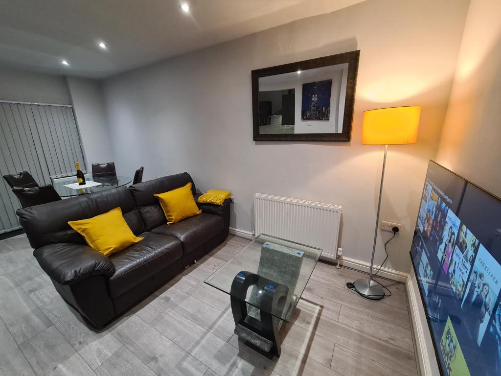 ein Wohnzimmer mit einem schwarzen Sofa und gelben Kissen in der Unterkunft Whole House - 4 Bedrooms - Parking - Sleeps 8 in Birmingham