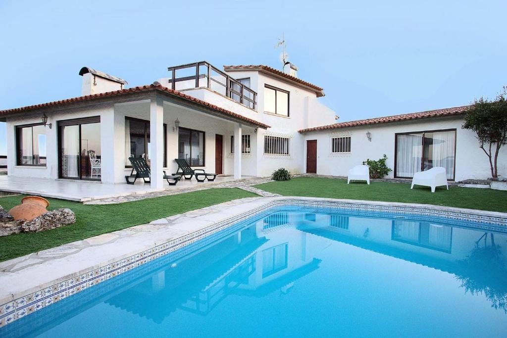 a villa with a swimming pool in front of a house at Sítio Do Louro Villa in São Martinho do Porto