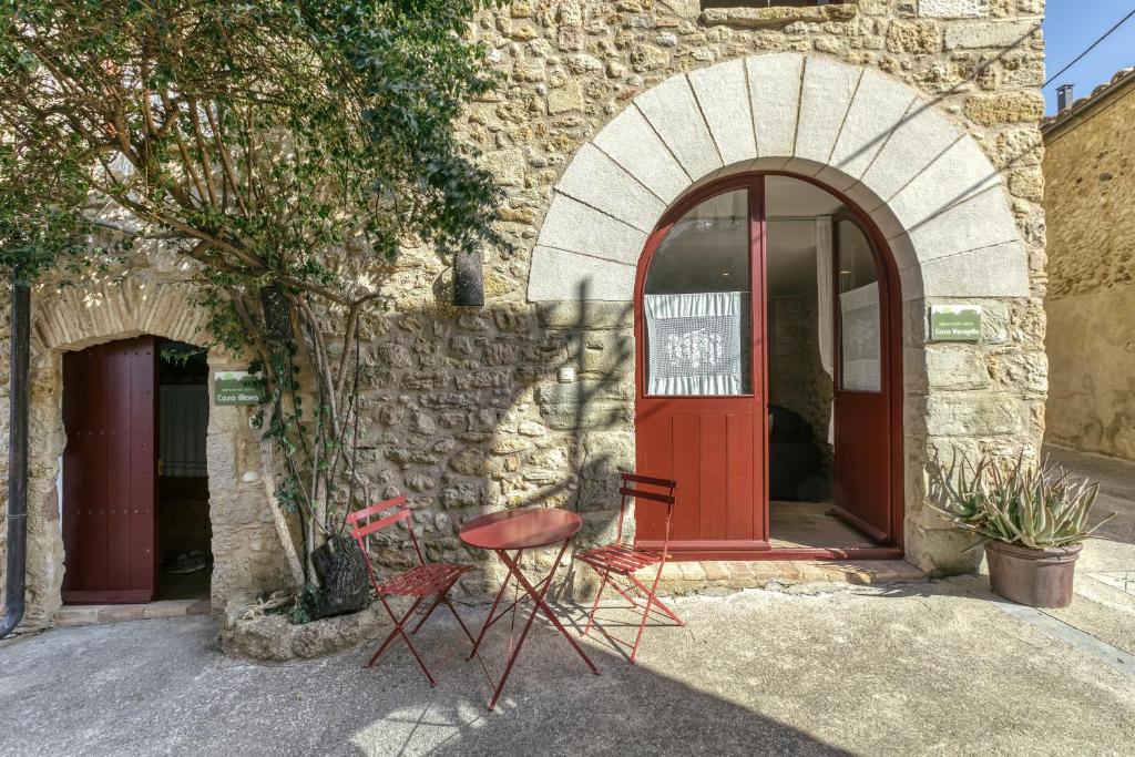 Deux chaises rouges à l'extérieur d'un bâtiment avec une porte rouge dans l'établissement Casa Vermella, à Orriols
