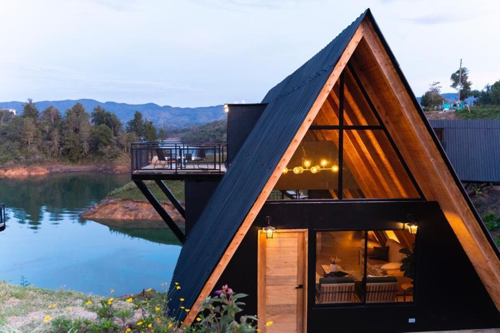 a house with a triangular roof on top of a lake at GRETEL CHALETS SUIZO in Guatapé