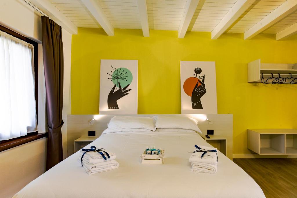 a bedroom with yellow walls and a bed with towels on it at Le Tofane, vivi la bellezza di Belluno - Primula in Sòis