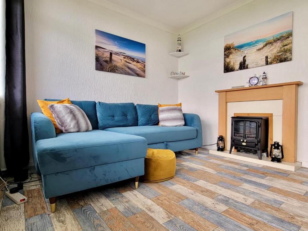 a blue couch in a living room with a fireplace at Charming 2 Bedroom Holiday Chalet in Withernsea