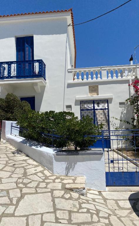 a white building with a blue balcony and some bushes at Katina's garden studio in Tinos