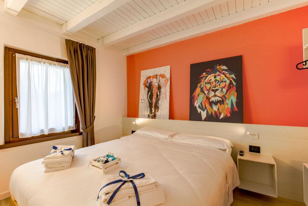 a bedroom with a white bed with an orange wall at Le Tofane, vivi la bellezza di Belluno - Ciclamino in Sòis