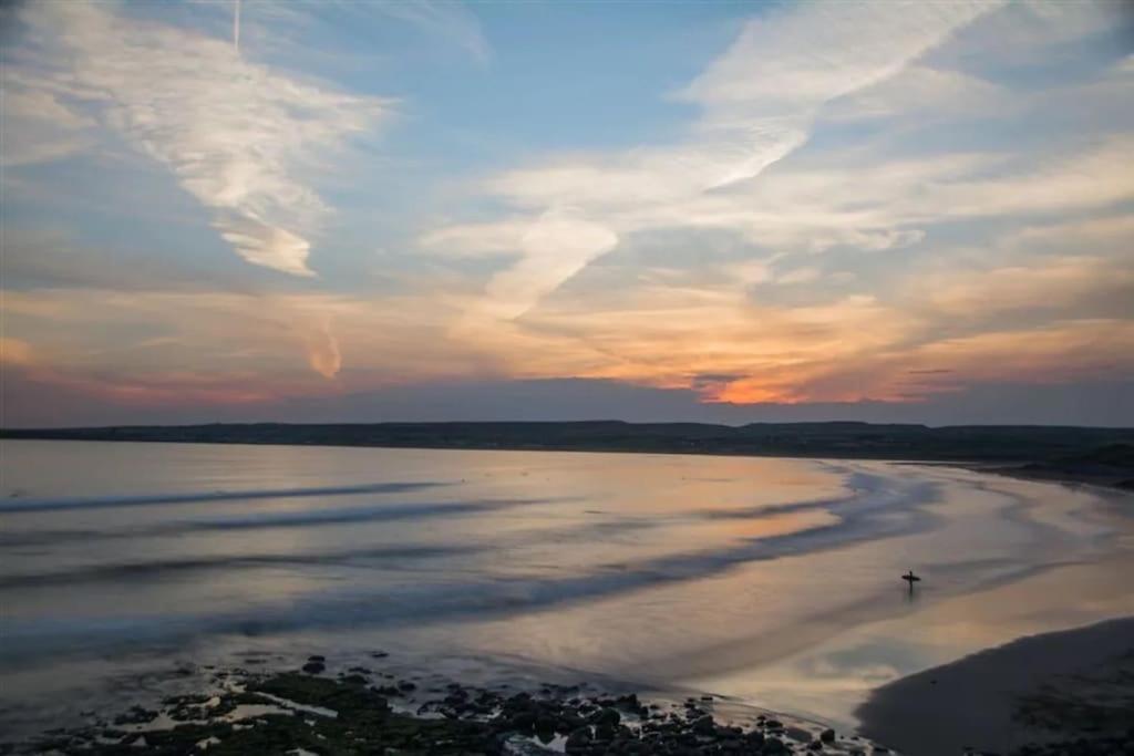 uma pessoa caminhando na praia ao pôr do sol em Village centre apartment em Lahinch