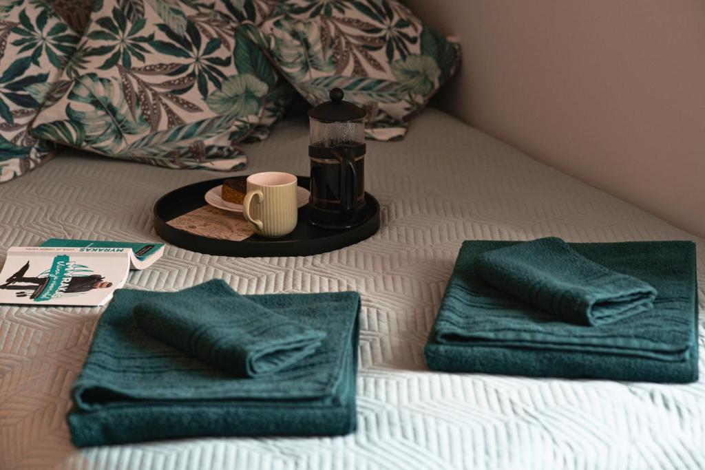a bed with two green towels and a tray with a bottle of wine at Kantreküla Apartment in Viljandi