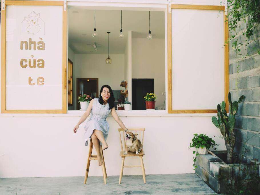 uma mulher de vestido sentada numa cadeira com um cão em Nhà của Te - Homestay & Tea room em Da Nang
