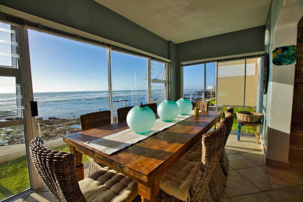 uma sala de jantar com mesa e cadeiras e o oceano em Atlantic Waterfront Cottage D3, 3 bedroom sea view em Swakopmund