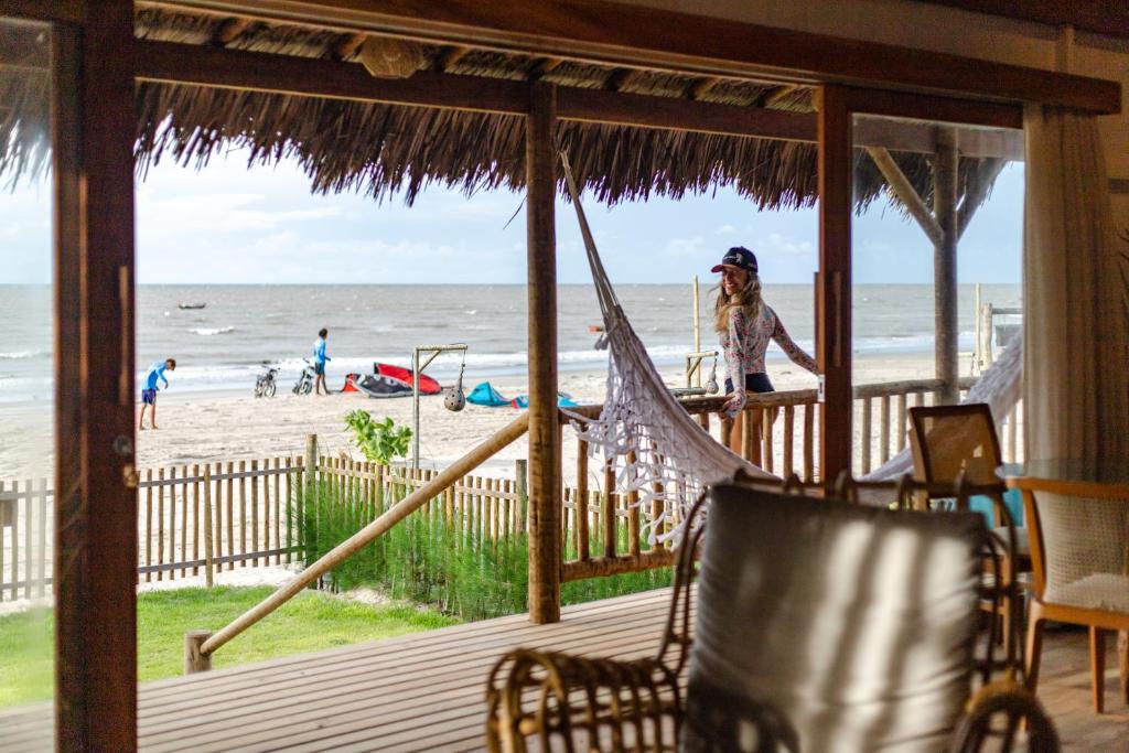 Eine Frau steht auf einer Veranda mit Blick auf den Strand. in der Unterkunft CASA na PRAIA DA BARRINHA Frente Mar in Barrinha