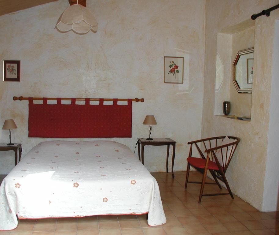 a bedroom with a bed with a red headboard and a chair at Chambres d’hôte l&#39;Amandière à Cucugnan in Cucugnan