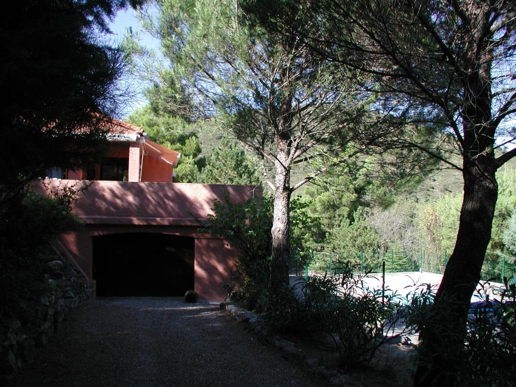 a red building with a garage and a tree at Chambres d’hôte l&#39;Amandière à Cucugnan in Cucugnan