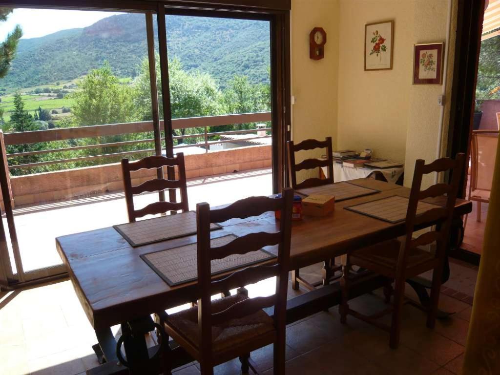 a dining room table with chairs and a large window at Chambres d’hôte l&#39;Amandière à Cucugnan in Cucugnan
