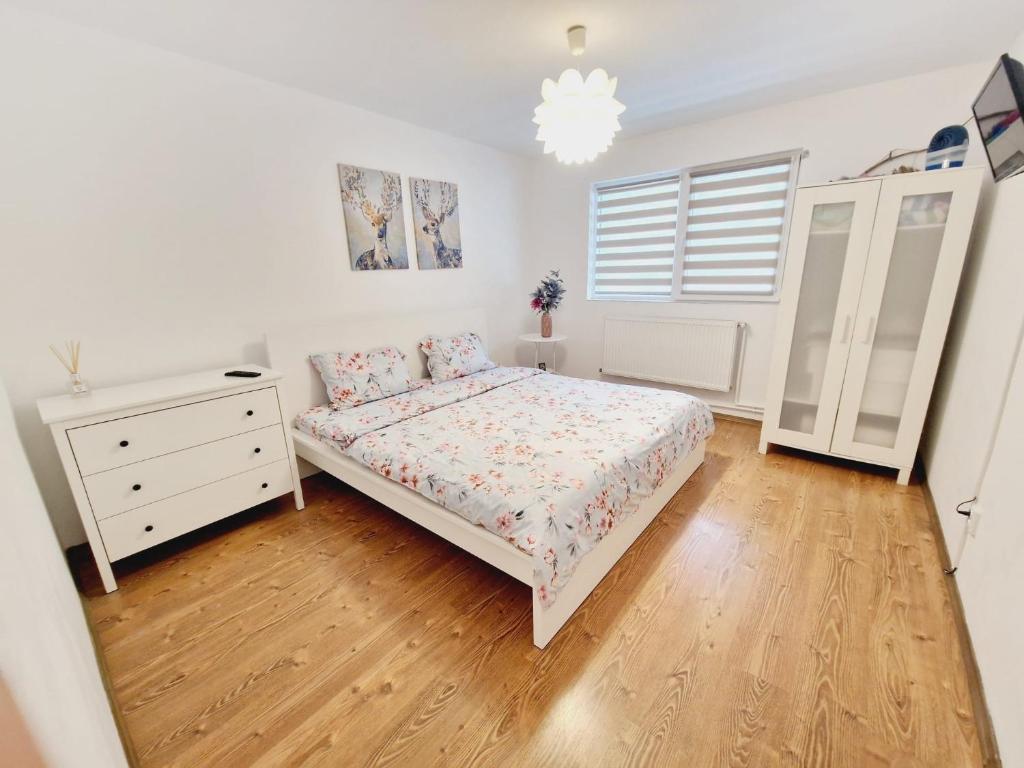a white bedroom with a bed and a dresser at DREAM Apartment in Sinaia