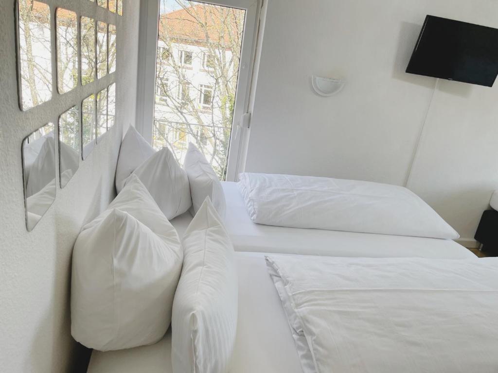 - une chambre avec 2 lits avec des oreillers blancs et une fenêtre dans l'établissement City Apartment Alt Saarbrücken, à Sarrebruck