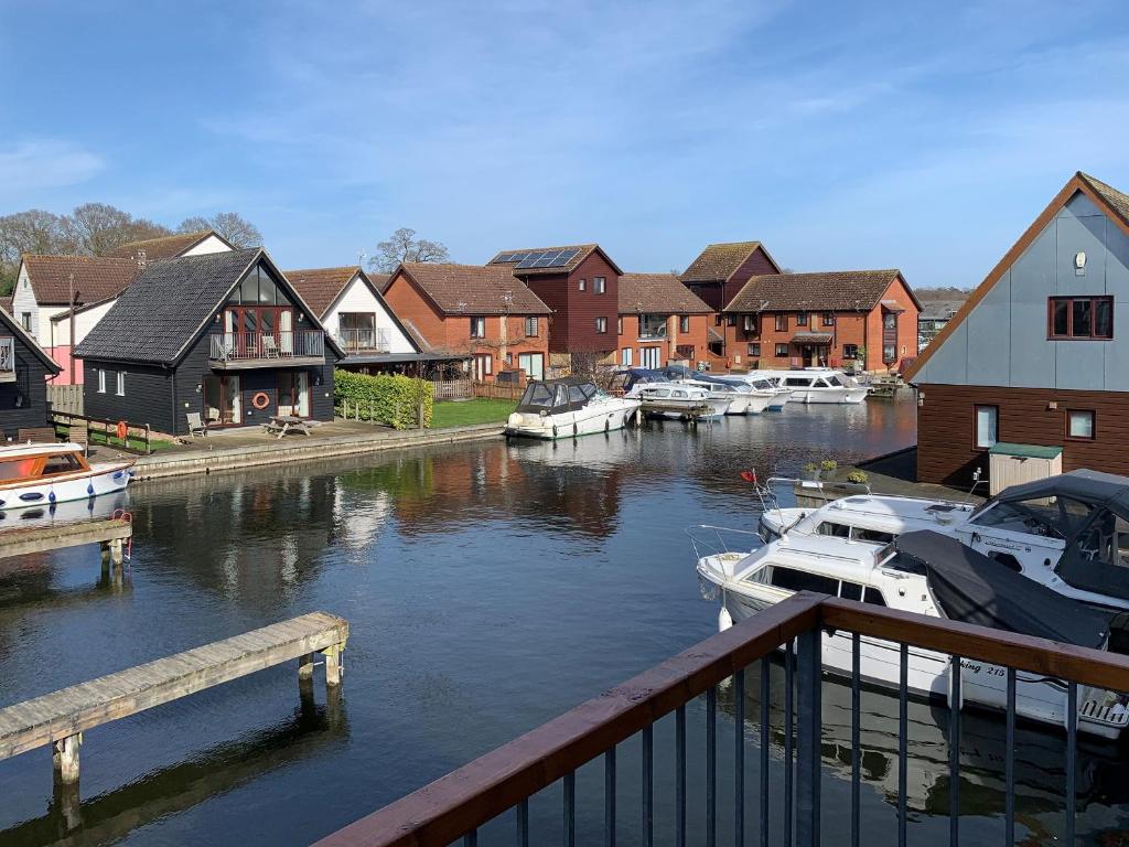 a group of boats docked in a river with houses at Wherrymere in Horning
