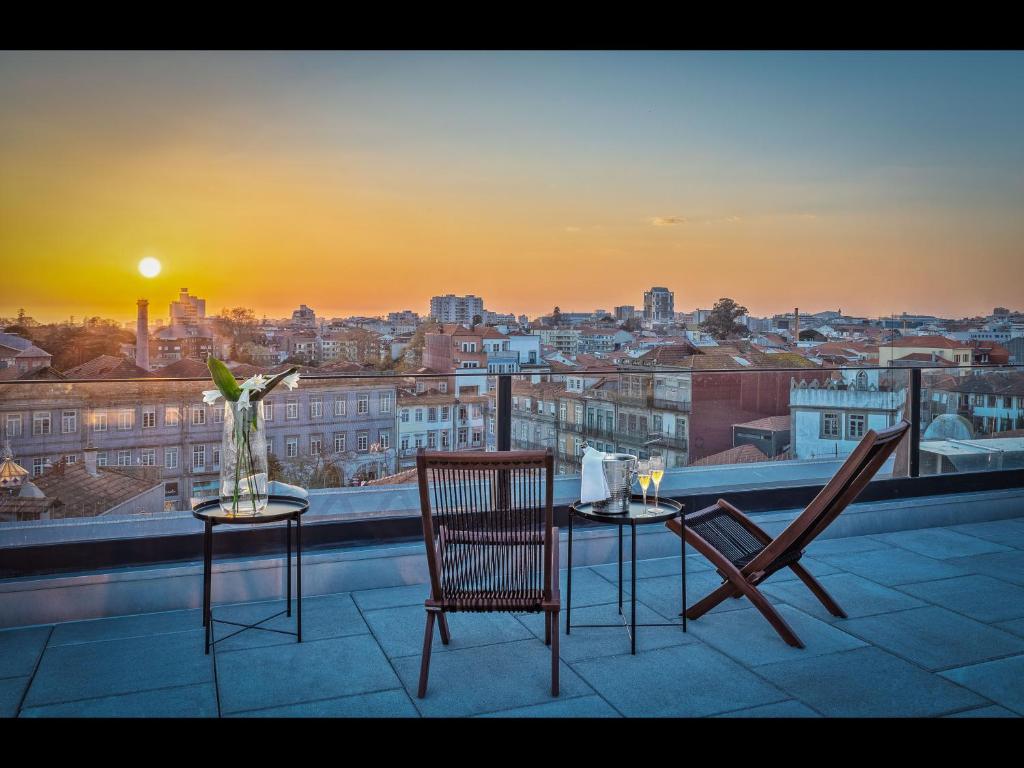 a table and chairs on a balcony with a view of a city at Hotel Moon & Sun Porto in Porto