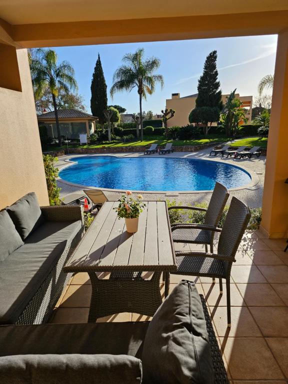 patio ze stołem i krzesłami oraz basenem w obiekcie Citadela I, Golfe, Pool and Falesia Beach w mieście Vilamoura