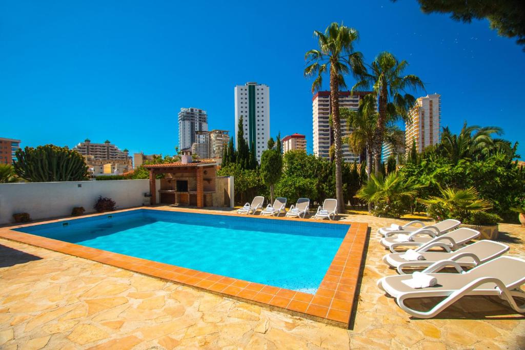 a swimming pool with lounge chairs and a city at Villa Cintya - PlusHolidays in Ifach