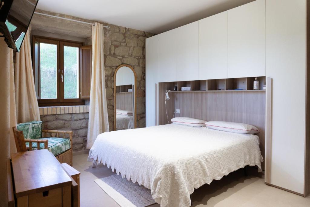 a bedroom with a large white bed and a chair at Le Colline di Giulia - Mini Casa ai piedi della collina in Venarotta