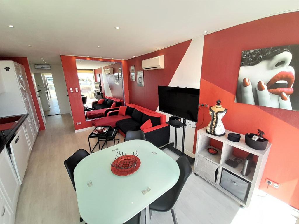 a living room with a white table and a tv at Appartements Village Naturiste Exultation Passion in Cap d'Agde