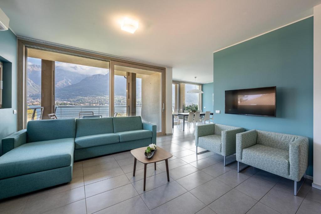een woonkamer met een bank en stoelen en een tv bij Bellagio Village- 4 Apartments by the lake - Seasonal Warm Pool and Sauna in Oliveto Lario