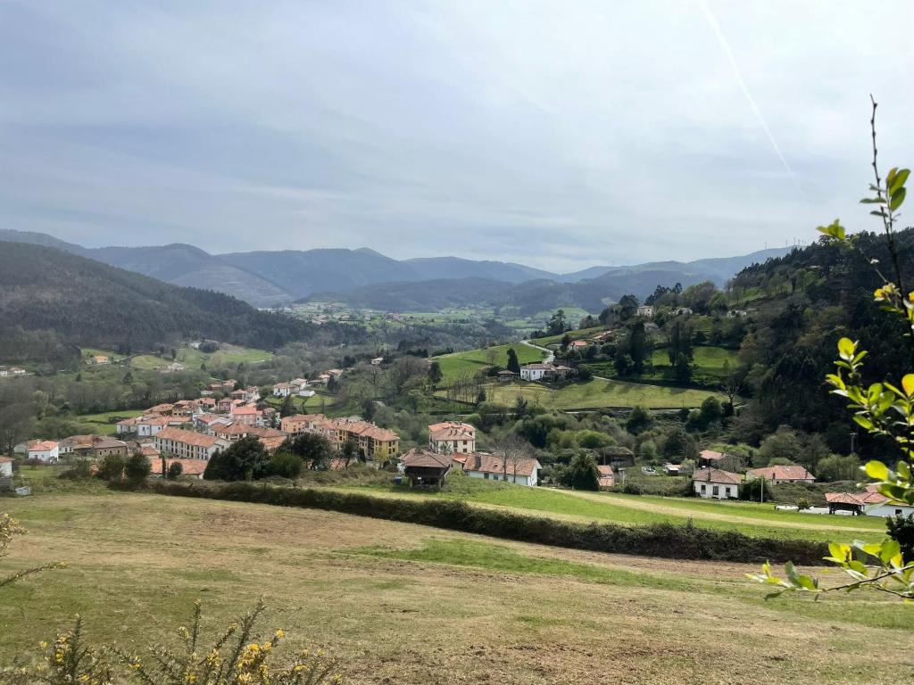 a village in the hills with mountains in the background at Casa Leonor in Soto de Luiña