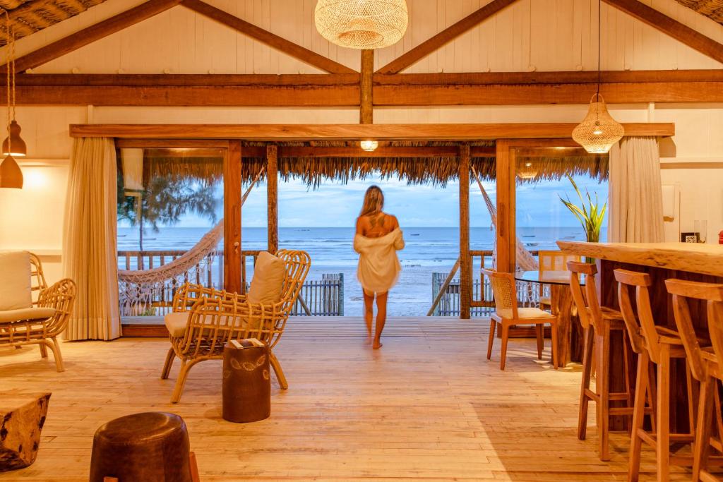 Una mujer caminando por una habitación con vistas al océano en CASA na PRAIA DA BARRINHA Frente Mar en Barrinha