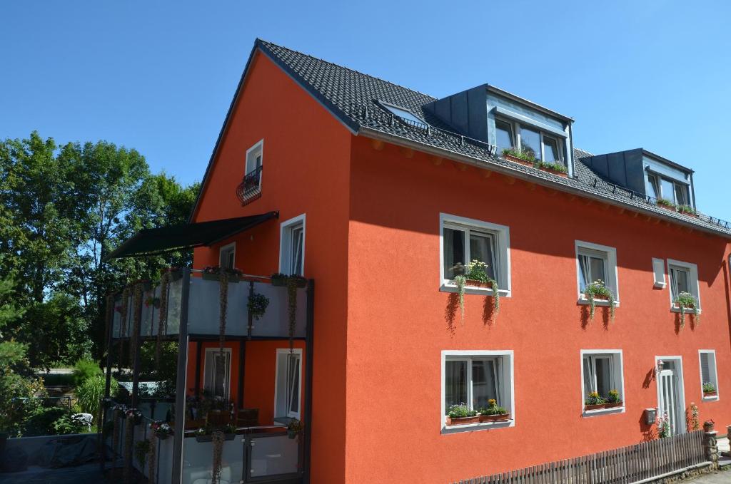 a red building with potted plants on the windows at Ferienwohnungen am Schambacher Weg in Riedenburg