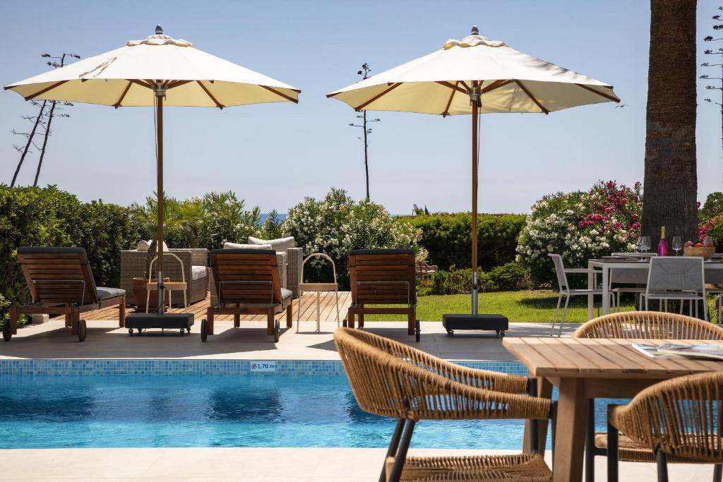 een patio met stoelen, tafels en parasols naast een zwembad bij Casa Girassol in Carvoeiro