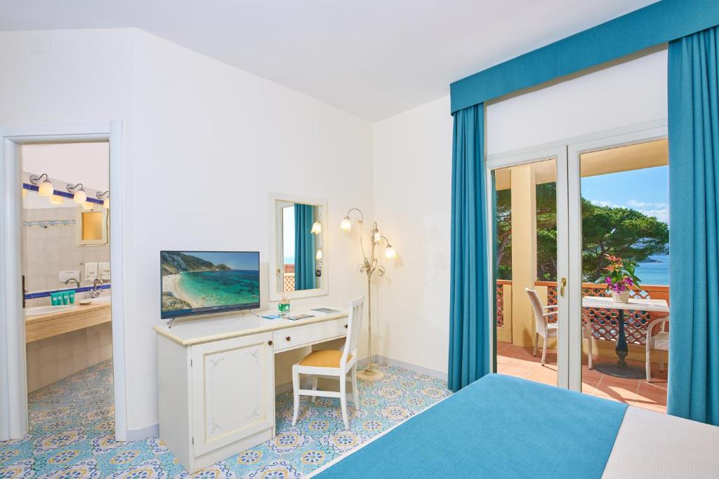 a bedroom with a bed and a desk with a mirror at Hotel Biodola in Portoferraio