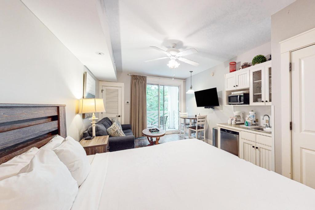 a bedroom with a white bed and a living room at Baytowne Wharf - Pilot House #323 in Destin