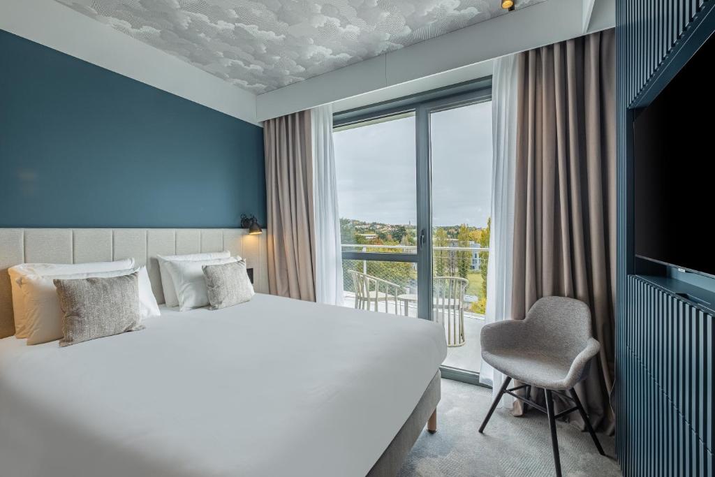 リモネストにあるKYRIAD LYON OUEST Limonestの大きなベッドと窓が備わるホテルルームです。