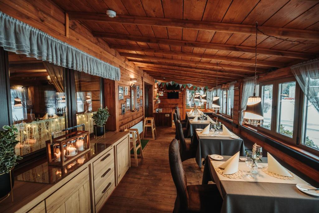 un comedor con mesas, sillas y ventanas en Agate Hotel, en Ozolnieki