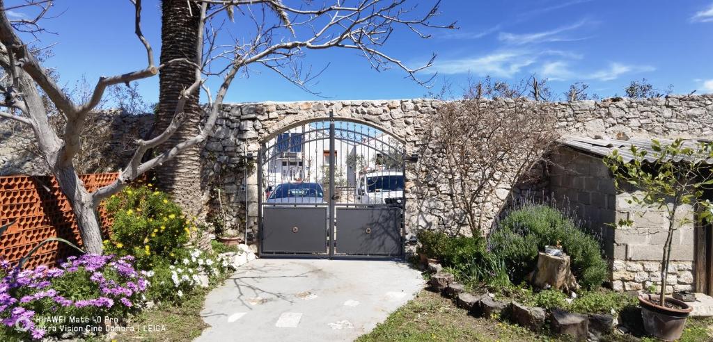 a gate in a stone wall with flowers at Guesthouse Palma in Mali Lošinj